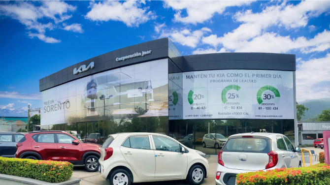 Edifcio del concesionario KIA en San Pedro Sula, Hoduras con varios autos kia estacionados afuera.