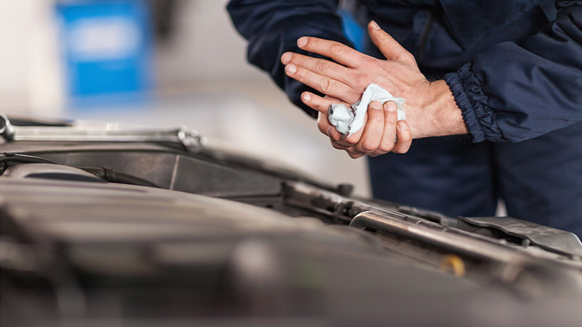 Mechanic wiping his hand in front of a open bonnet