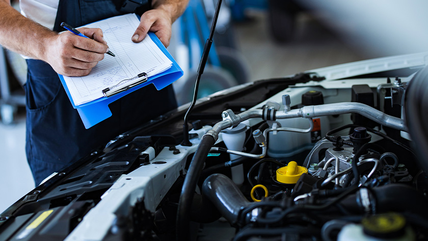 Mechanic is checking the inspection list in front of a open bonnet 