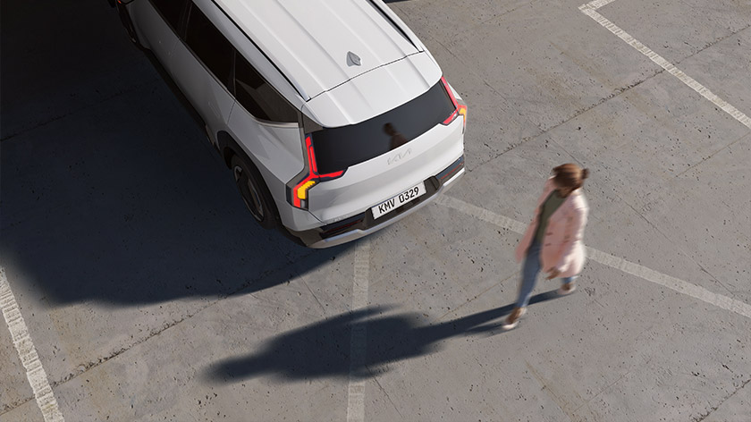 Top-down view of an EV9 reversing, with a person walking behind