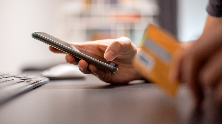 Woman using smartphone with credit card in her hand